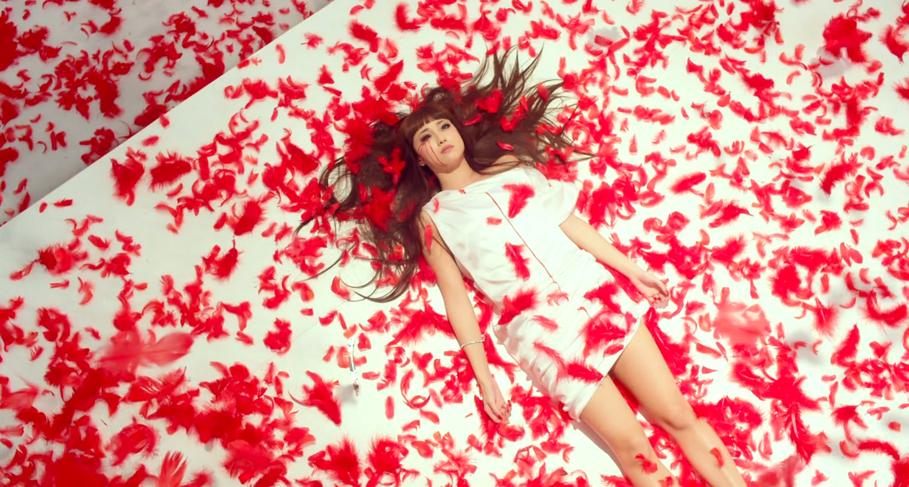 Woman dressed in white surrounded by red feathers